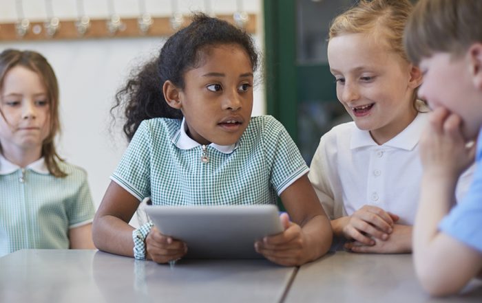 Schoolgirls and boy using digital tablet in classroom lesson at primary school